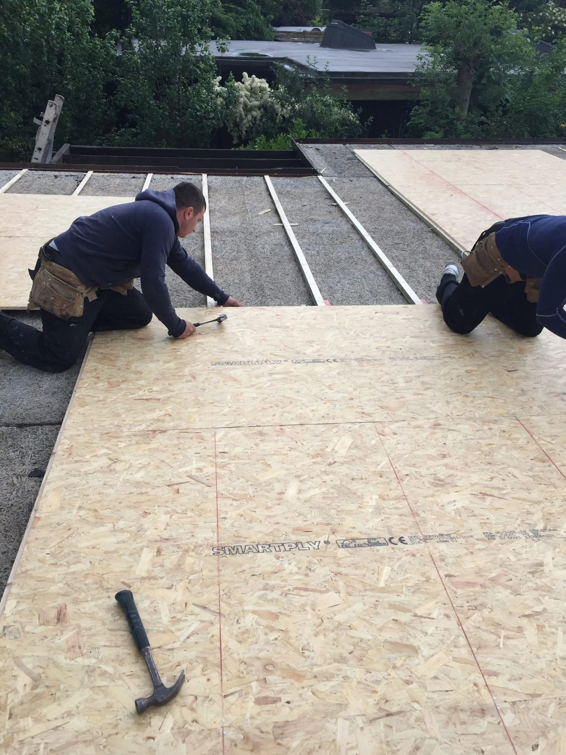 Workers nailing wood down for roof.